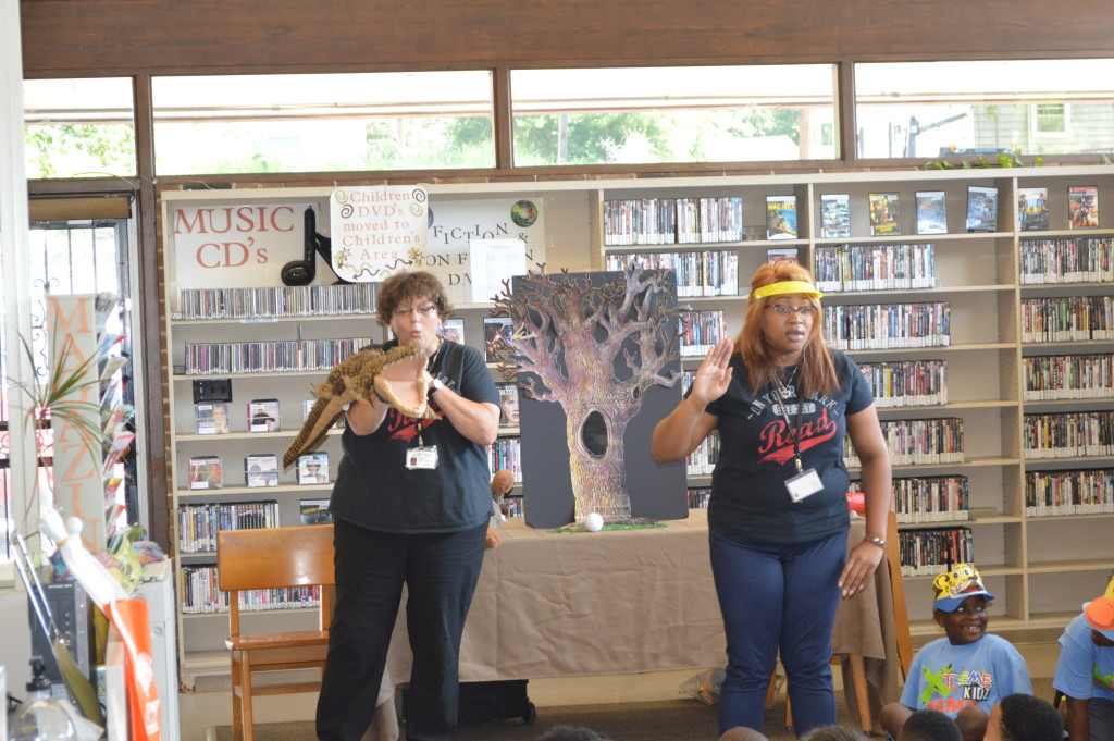 Five Points West Regional Library storytellers Fontaine Alison, holding alligator, and Candice Hardy entertain summer campers from Faith Chapel Christian Center during Summer Reading program at Wylam Library.