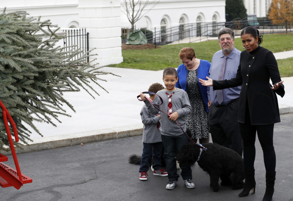 First lady Michelle Obama, right, acompanied by nephews Aaron, left, and Austin Robinson, and growers Mary and Dave Vander Velden, of Oconto, Wis., gestures as she receives the Official White House Christmas Tree at the White House in Washington, Friday, Nov. 25, 2016. The Balsam-Veitch fir is 19 feet tall and 12 feet wide. (AP Photo/Alex Brandon)