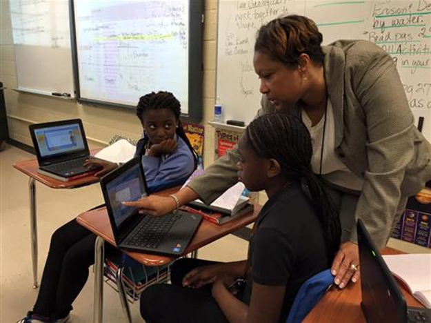 An instructor at Green Acres works with students with a set of laptops being used in class. A new grant will now help the school buy laptops for every class. (Chanda Temple, provided photos)