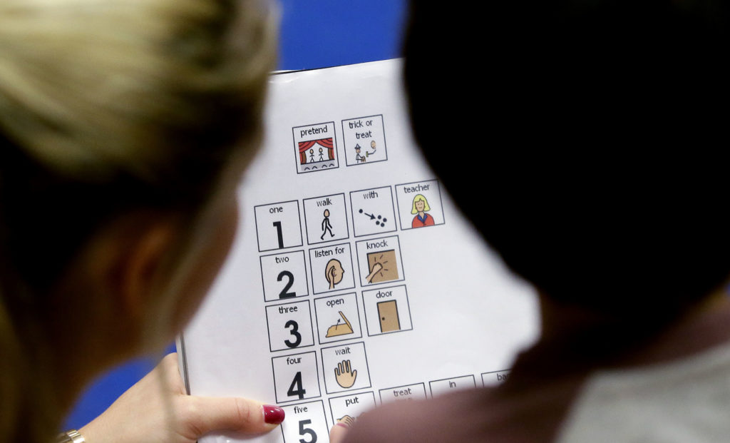 A preschool student with autism and educator go over visual prompts. (LM Otero, The Associated Press)