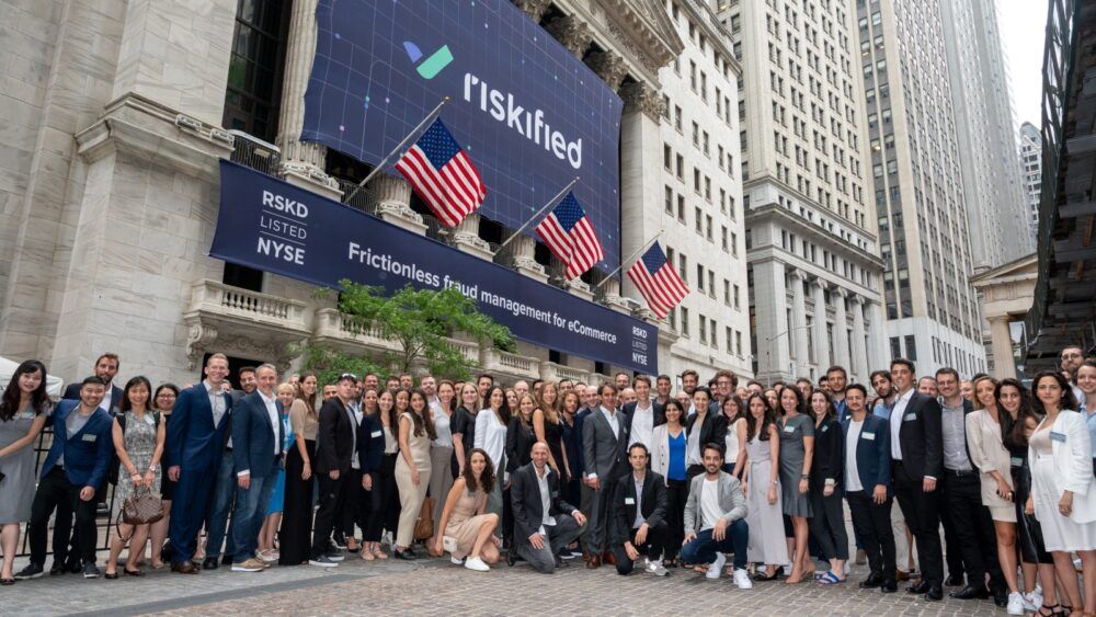 Riskified employees in front of the New York Stock Exchange. Riskified, which went public last July, works with clients including Acer, Trip.com and Ticketmaster. (CRC Media)