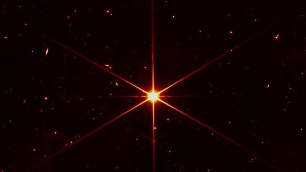 While the purpose of this image was to focus on the bright star at the center for alignment evaluation, Webb's optics and the Near Infrared Camera are so sensitive that the galaxies and stars seen in the background show up. This image of the star, which is called 2MASS J17554042+6551277, uses a red filter to optimize visual contrast. (NASA/STScI)