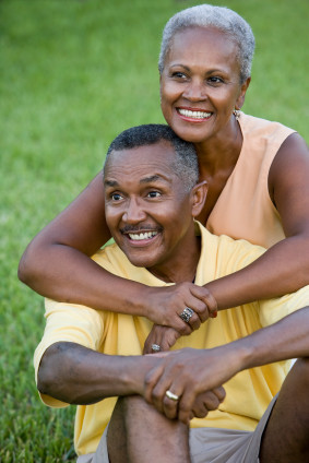 Happy senior African American couple sitting on grass together