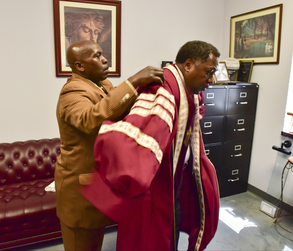 Assistant minister Charles August helps Dr. Wesley into his robe before service. Dr. Michael W. Wesley, Sr. serves as pastor of  the Greater Shiloh Missionary Baptist Church located on Jefferson Avenue in Birmingham, Alabama. Dr. Wesley leads two services on Sunday mornings and is preparing to host the 110th Annual National Baptist Congress. Photo by Frank Couch