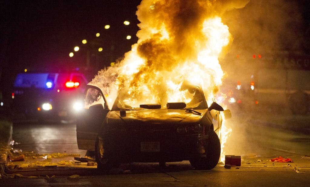 A car burns as a crowd of more than 100 people gathers following the fatal shooting of a man in Milwaukee, Saturday, Aug. 13, 2016. The Milwaukee Journal Sentinel reported that officers got in their cars to leave at one point, and some in the crowd started smashing a squad car's window, and another vehicle, pictured, was set on fire. The gathering occurred in the neighborhood where a Milwaukee officer shot and killed a man police say was armed hours earlier during a foot chase. (Calvin Mattheis, Milwaukee Journal-Sentinel via The Associated Press)