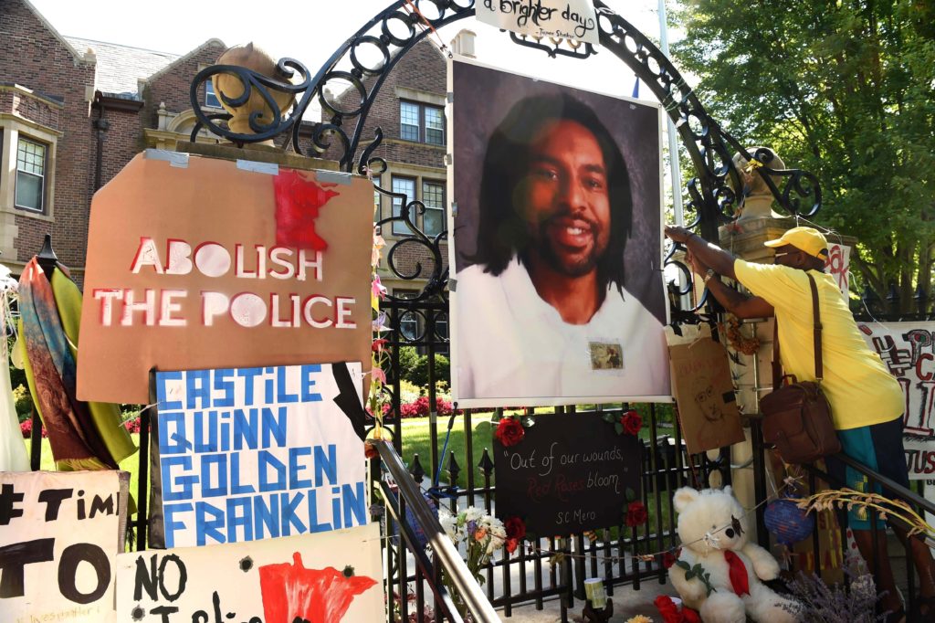 In this Sunday, July 24, 2016, file photo, King Demetrius Pendleton hangs a sign on the gate of the Governor's Residence in St. Paul, Minn., as protesters demonstrate against the July 6 shooting death of Philando Castile by a St. Anthony police officer making a traffic stop in Falcon Heights, Mich. The Minnesota Bureau of Criminal Apprehension has been investigating the shooting by St. Anthony police Officer Jeronimo Yanez of Castile. The agency said Wednesday, Sept. 28, that it turned over its findings to prosecutors. (Scott Takushi/St. Paul Pioneer Press via AP, File)