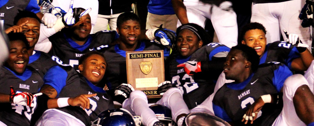 Ramsay High football players pose with the trophy they earned by winning their Class 6A semifinal 25-14 over Austin on Friday, Nov. 25, 2016, at Birmingham's Lawson Field Stadium. The victory sends the Rams to the state championship game against Opelika at Auburn's Jordan-Hare Stadium. (Ariel Worthy, The Birmingham Times)