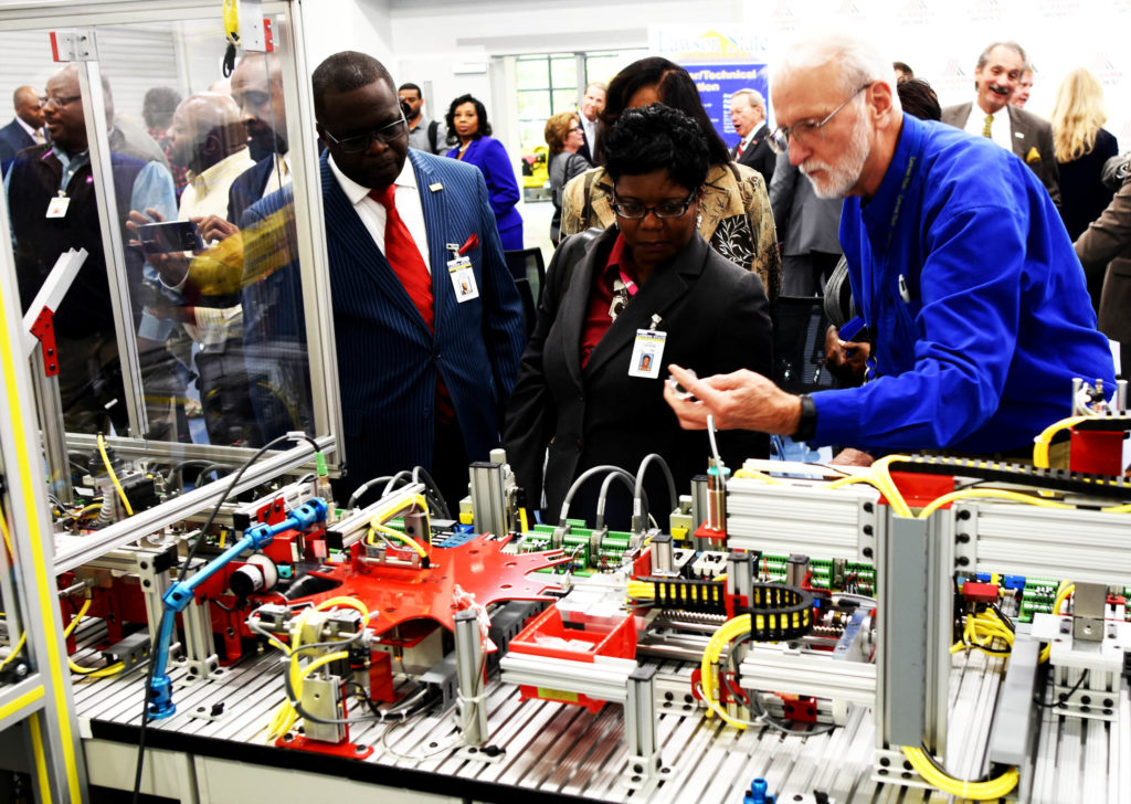 Rich Raymond (right), industrial electronics instructor at the Bessemer campus of Lawson State Community College, demonstrates some of the tasks performed using robotics in the class. (Solomon Crenshaw Jr., special to The Times)