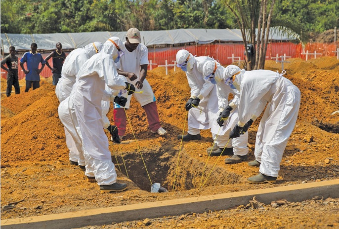 A burial team lowers the body of an Ebola victim into a grave in a new cemetery in Liberia. (Unmeer photo)