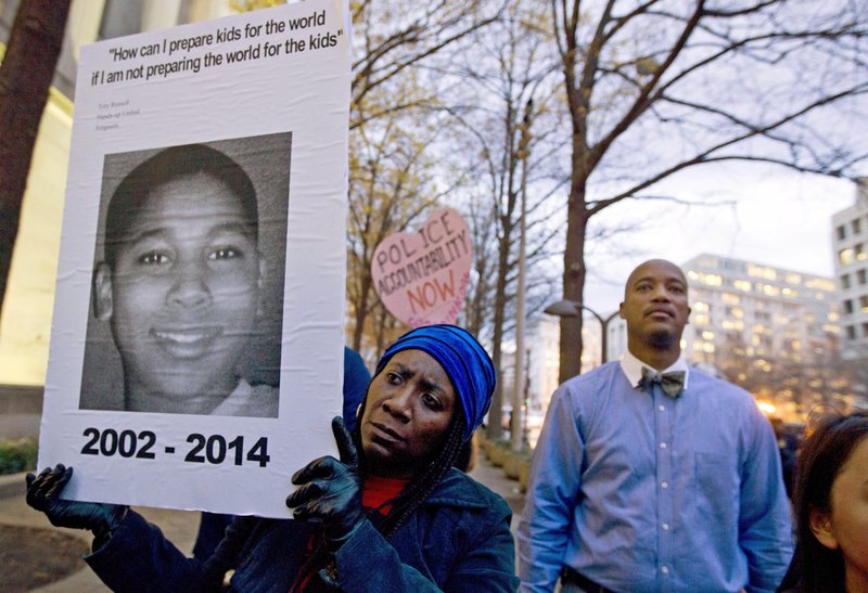  FILE – In this Dec. 1, 2014, file photo, Tomiko Shine, left, holds a sign with a photo of Tamir Rice, a boy fatally shot by a Cleveland police officer, while protesting a grand jury’s decision in Ferguson, Mo., not to indict police officer Darren Wilson in the shooting death of Michael Brown, during a demonstration in Washington. Cleveland Police Chief Calvin Williams announced Tuesday, May 30, 2017, that Timothy Loehmann, the police officer who shot and killed the 12-year-old boy, has been fired for inaccuracies on his job application, while the officer who drove the patrol car the day of the Nov. 22, 2014, shooting, Frank Garmback, has been suspended for 10 days for violating a tactical rule for his driving that day. (AP Photo/Jose Luis Magana, File)