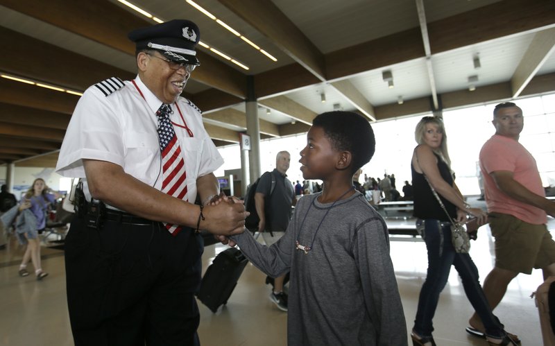 Cristopher Goods, 10, right, offers congratulations to Southwest Airlines captain Louis Freeman before Freeman piloted his last flight for the airline before his retirement in Dallas, Thursday, June 8, 2017. Freeman was the first African-Americansto become a chief pilot at a major U.S. airline and is retiring after a 36-year career that saw big changes in aviation. His most memorable flight carried the body of civil rights icon Rosa Parks. (AP Photo/LM Otero)