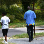 Wesley Holmes strolls and talks with a young fellow