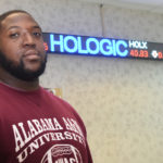 Vernon Jr. stands near the scrolling electronic stock ticker in A&M’s School of Business.
