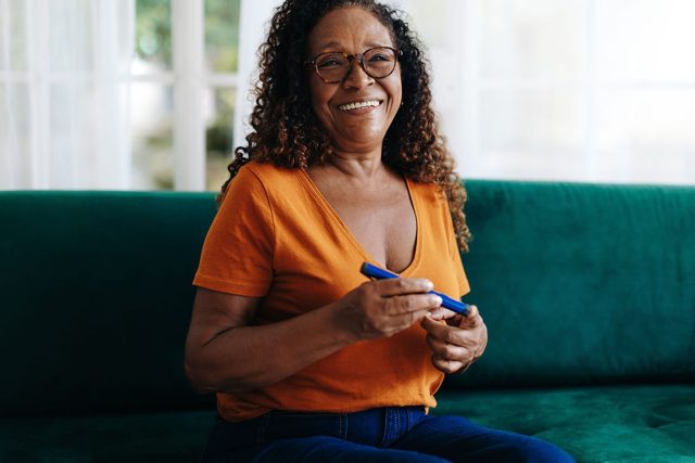 Happy senior woman controlling her blood glucose with an insulin delivery