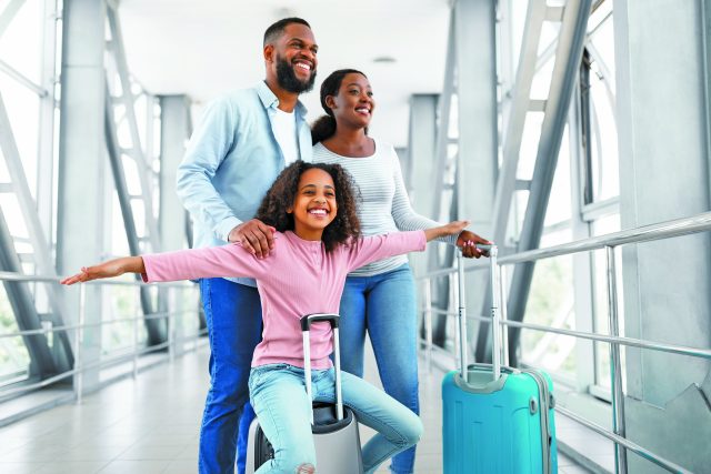 Happy black family traveling with kid, walking in airport