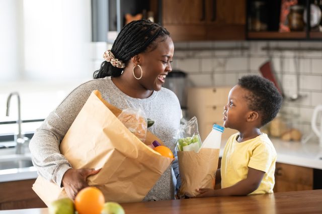 Cheerful African-American mother and son in the kitchen. Son hel