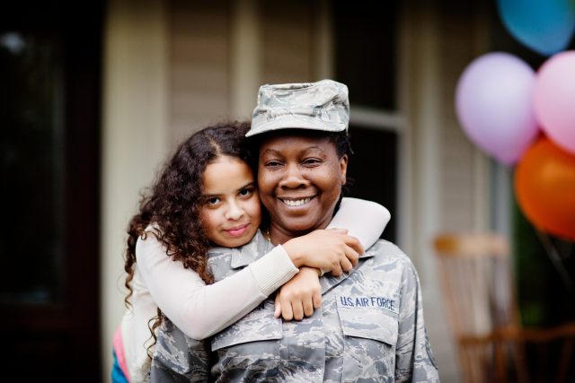Portrait of female solder receiving hug from girl