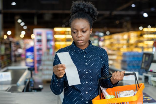 Woman checking supermarket receipt feeling concerned about expenses